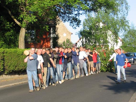 Der Maibaum wird auf Schultern im Ort zum Kirchplatz getragen